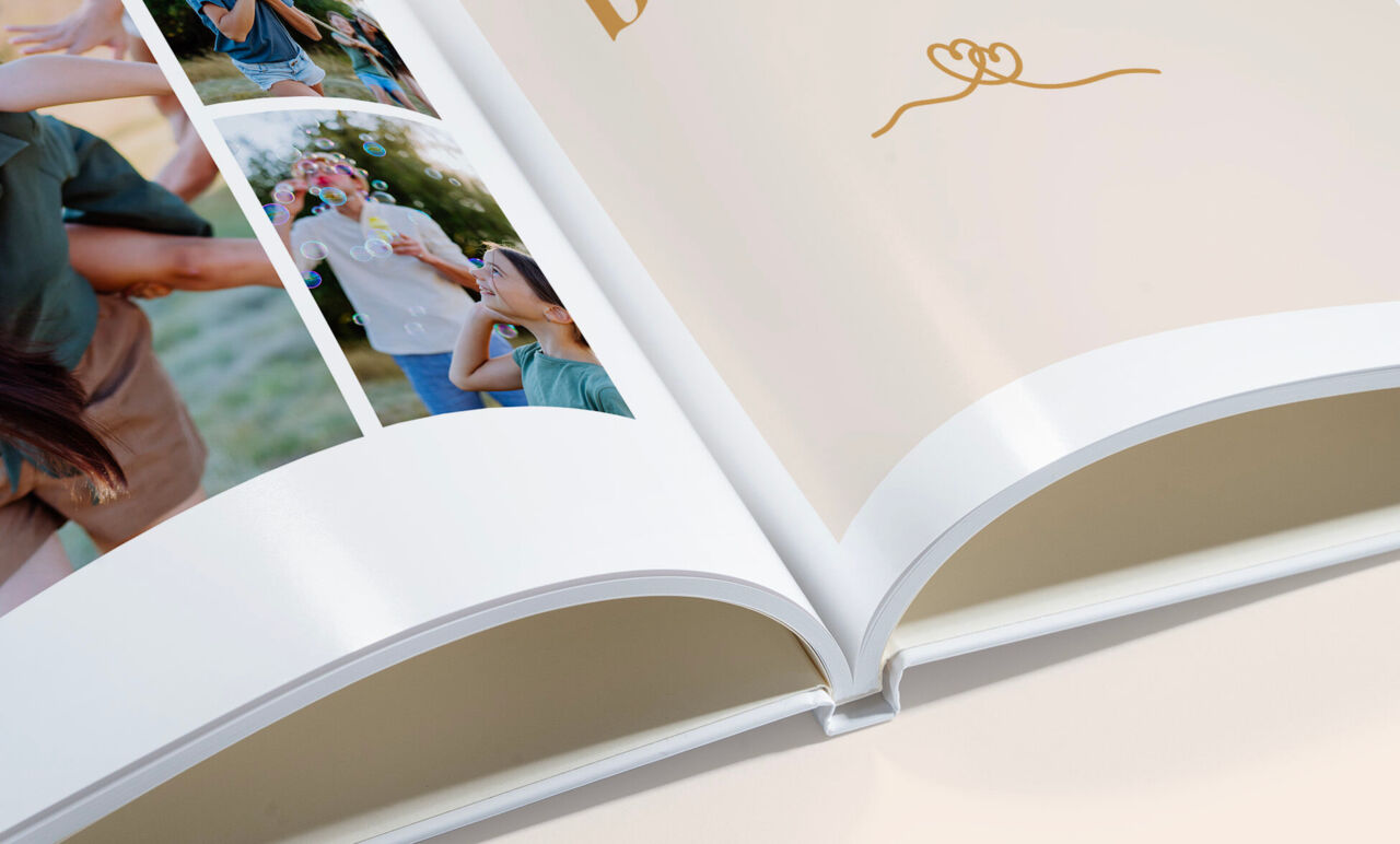Álbum de fotos abierto mostrando una página con collage de fotos de boda a la izquierda y una página en blanco con un dibujo dorado
