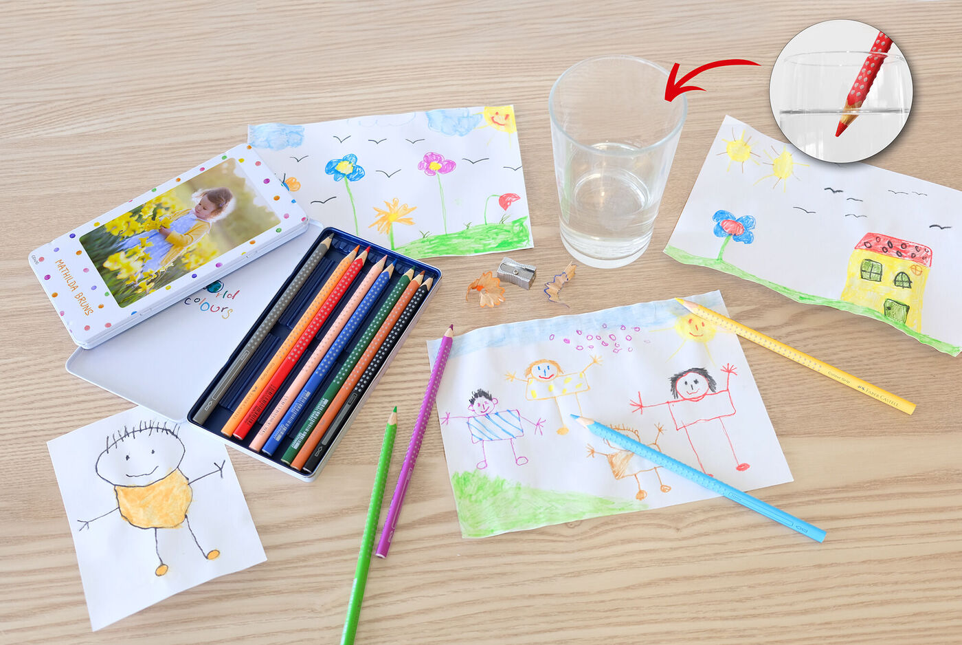 Dibujos infantiles coloridos están sobre una mesa, con material de pintura listo.
